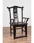 Dark patina elmwood scholar's chair set on wooden floor against a white brick wall indoors.
