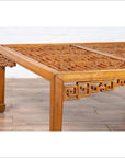 Brown elmwood square coffee table with open fretwork and horse-hoof legs on a wooden floor indoors.