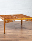 Brown elmwood square coffee table with open fretwork and horse-hoof legs, indoor setting.