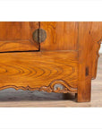 Close-up of brown elmwood low two-door cabinet with everted flanges, scrolls, and a round metal handle.