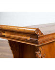 Close-up of brown elmwood two-door low cabinet with ornate scrolls, everted flanges, and carved details.