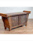 Brown elmwood low two-door cabinet with everted flanges and scrolls on a wood floor indoors.