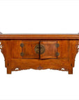 Brown elmwood two-door low cabinet with everted flanges and scrolls, central doors visible, indoors setting.