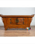 Brown elmwood two-door low cabinet with everted flanges and scrolls on wood floor next to a color chart.