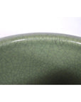 Close-up of green celadon ceramic bowl showing fine crackle glaze pattern on rim and surface.