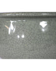 Close-up of green celadon ceramic bowl with glossy crackle glaze and rounded rim.