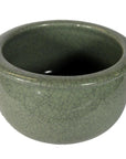 Close-up of green celadon ceramic bowl with wide rim and crackle glaze, hand-thrown finish visible.
