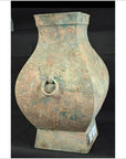 Brown Chinese Han Dynasty ceramic hu vessel with square base and ring handle against a black background, close-up.