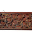 Close-up of a Chinese hand carved wood plaque featuring swirling floral patterns in muted gold and brown tones.