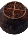 Dark lacquered bamboo basket with round shape and wooden cross-shaped lattice top, close-up on plain background.