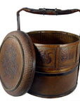 Brown wicker Chinese wedding basket with tall handle and round lid, decorative pattern visible, close-up view.