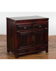Reddish black lacquered wood Chinese side cabinet with brass handles, Late Qing Dynasty, set against a white wall.
