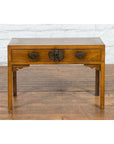 Brown elm Late Qing Dynasty Chinese desk with two drawers and ornate brass hardware on wooden floor by white brick wall.