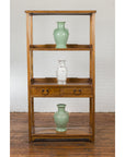 Tall wooden bookcase with three shelves and two drawers, displaying two green vases and one clear vase on shelves.