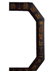 Close-up of octagonal vintage Chinese leather frame with gold calligraphy on a dark background.