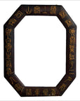 Close-up of octagonal dark wood Chinese leather frame with gold calligraphy on white background.