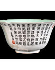 White porcelain bowl with black calligraphy and a red seal, set against a black background, close-up.