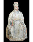 Seated 17th century Ming Dynasty terracotta court figure statuette with faded paint on black background.