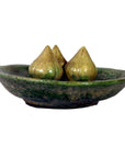 White ceramic Ming Dynasty plate with three teardrop-shaped glazed objects, close-up view on plain background.