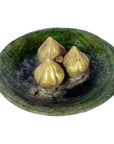 White porcelain Ming Dynasty plate with three small, brown, fig-shaped objects, close-up.