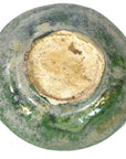Close-up of a weathered ceramic bowl base with mottled green glaze, resembling Chinese Ming Dynasty food plates.