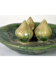 Green glazed ceramic Ming Dynasty plate with three rustic, cone-shaped decorations, close-up view.