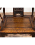 Brown elmwood Ming Dynasty chair with curved arms, carved backrest, visible wood grain on wooden floor indoors.