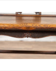 Close-up of brown elmwood Ming Dynasty chair with ornate wood grain and carved decorative edge.