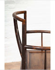 Close-up of dark wood elm Ming Dynasty chair with carved details, set against a white brick wall indoors.