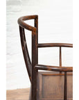 Close-up of dark wood elm Ming Dynasty chair with carved details, set against a white brick wall indoors.