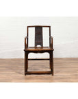 Brown elmwood chair with Chinese Ming Dynasty design on wooden floor against a white wall indoors.