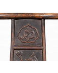 Close-up of brown elmwood Chinese Ming Dynasty chair with carved floral patterns, white background.
