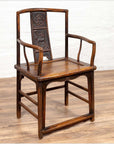 Brown elmwood chair with carved floral and animal backrest, Ming dynasty style, on a wooden floor indoors.