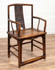 Brown elmwood chair with carved floral and animal backrest, Ming dynasty style, on a wooden floor indoors.