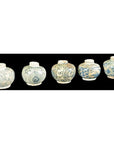 Close-up of five small round Ming Dynasty Swatow Ware jars with blue floral and geometric patterns on black.