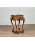 Dark wood Ming style incense stand with cabriole legs and carved apron, indoors against a white brick wall.