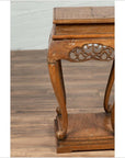 Close-up of a dark wood Ming style incense stand with cabriole legs and carved apron on a wooden floor.