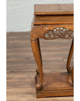 Close-up of a dark wood Ming style incense stand with cabriole legs and carved apron on a wooden floor.