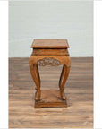 Brown wooden Ming style incense stand with cabriole legs and carved apron, shown on a wooden floor indoors.