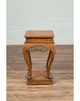 Brown wooden Ming style incense stand with cabriole legs and carved apron, shown on a wooden floor indoors.