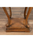 Close-up of brown wooden Chinese Ming style incense stand with cabriole legs and carved apron on wood floor.