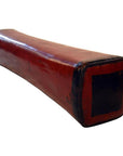Rectangular red lacquered Chinese opium pillow with black ends on a white background.