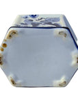 Close-up of blue and white ceramic hexagonal bottle base with vintage design and visible wear on the edges.