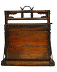 Black and brown carved wood Chinese picnic box with ornate details and metal handle, close-up on plain surface.