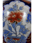 Close-up of Chinese porcelain electric lamp with ornate vase design, large red flower, blue leaves, and gold accents.