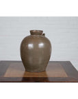 Glazed ceramic water jug with petite spout, 19th-century Qing Dynasty, on wooden table by white brick wall.