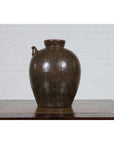 Glazed ceramic water jug with petite spout, 19th-century Qing Dynasty, on wooden table by white brick wall.