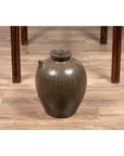 Glazed ceramic Chinese Qing Dynasty 19th-century water jug with petite spout on wooden floor under table.