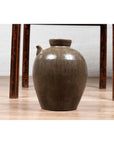 Blue glazed ceramic water jug with petite spout on wooden floor beneath a table, Qing Dynasty, 19th century.
