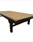 Natural rattan coffee table with decorative legs and flat top, displayed on a white background.